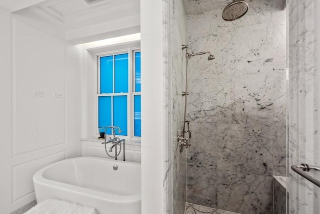bathroom featuring a freestanding tub and a marble finish shower