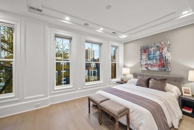 bedroom featuring recessed lighting, a raised ceiling, and wood finished floors