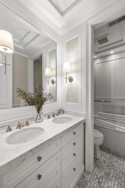 bathroom with double vanity, toilet, visible vents, and a sink