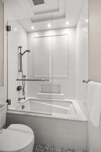bathroom with recessed lighting, toilet, tiled shower / bath combo, and visible vents