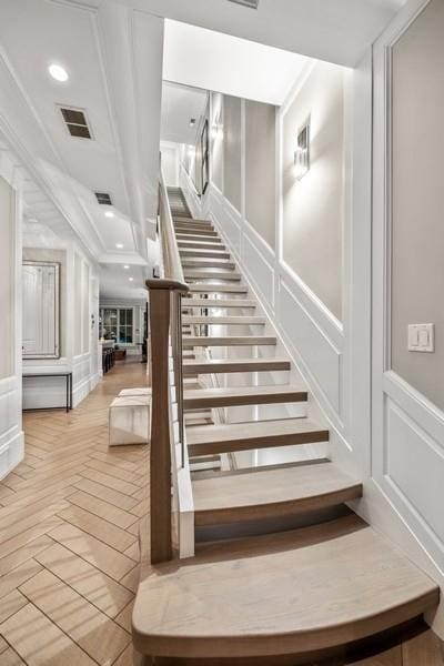 stairs with recessed lighting, visible vents, a wainscoted wall, and a decorative wall