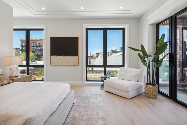bedroom featuring recessed lighting, baseboards, wood finished floors, and a tray ceiling