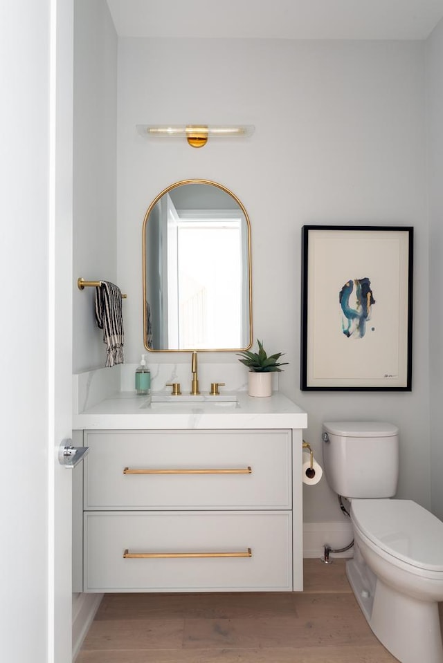 bathroom with vanity, baseboards, toilet, and wood finished floors