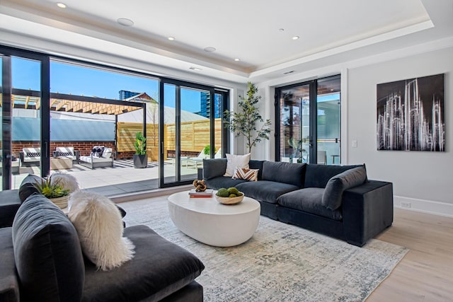 living room with a tray ceiling, recessed lighting, wood finished floors, and a wealth of natural light
