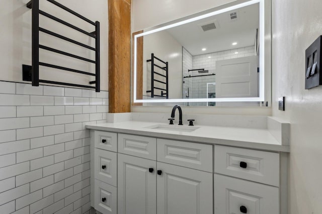 bathroom with radiator, a tile shower, vanity, and visible vents