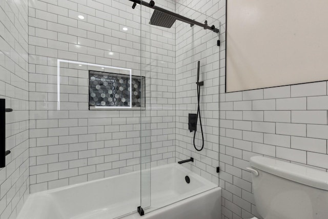 bathroom with toilet, shower / washtub combination, and tile walls