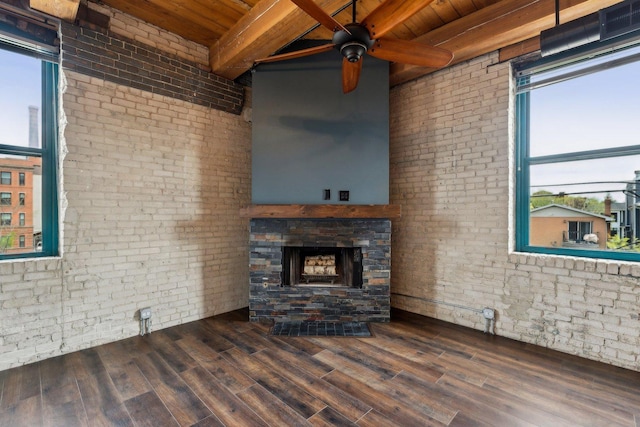 unfurnished living room with beamed ceiling, ceiling fan, wood ceiling, and brick wall