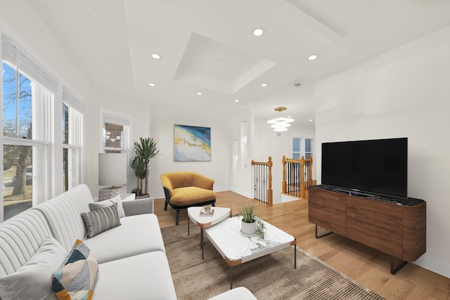 living room featuring baseboards, a tray ceiling, recessed lighting, and light wood-style flooring
