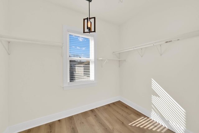 walk in closet featuring a notable chandelier and wood finished floors