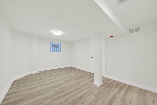 finished basement featuring baseboards, visible vents, and light wood-type flooring