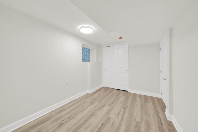 unfurnished bedroom featuring baseboards, light wood finished floors, and a closet