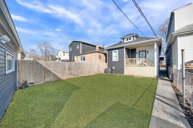 view of yard featuring a fenced backyard, central AC, and covered porch