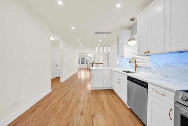 kitchen featuring hanging light fixtures, a sink, light wood-style floors, stainless steel appliances, and white cabinetry