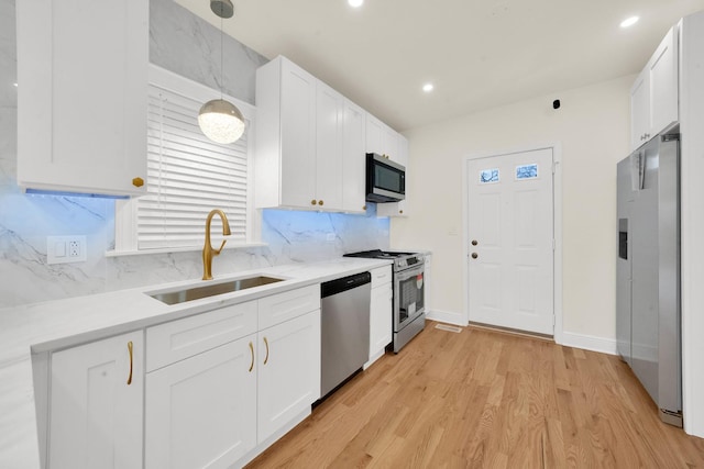 kitchen featuring white cabinets, appliances with stainless steel finishes, a sink, light countertops, and tasteful backsplash