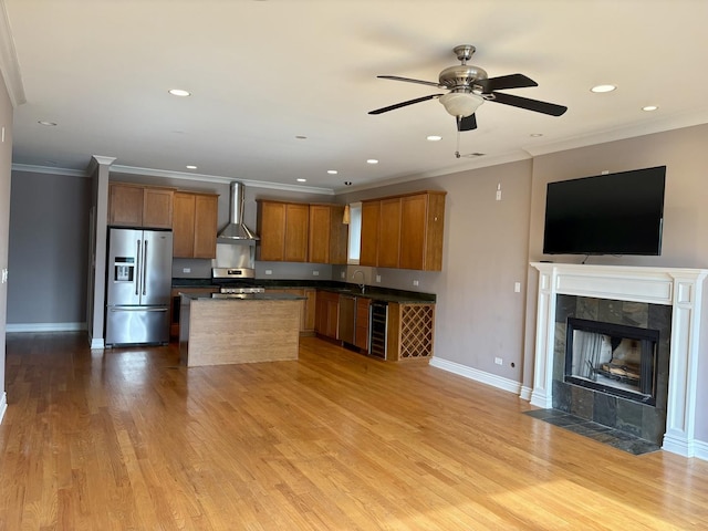 kitchen featuring appliances with stainless steel finishes, wall chimney range hood, open floor plan, dark countertops, and wine cooler