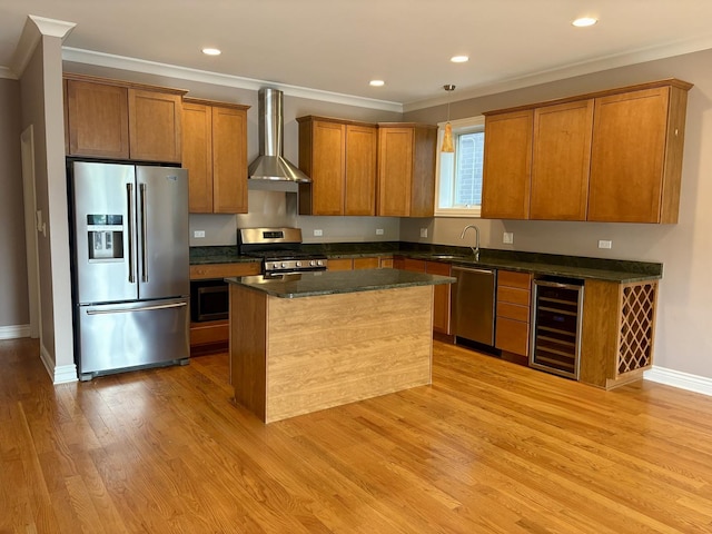 kitchen featuring appliances with stainless steel finishes, wall chimney range hood, beverage cooler, brown cabinetry, and ornamental molding