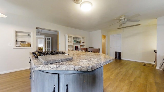 229 E Jefferson St, Arcola, IL 61910 - kitchen with a ceiling fan, baseboards, light countertops, light wood finished floors, and a center island