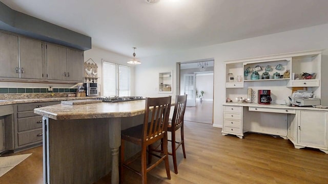 229 E Jefferson St, Arcola, IL 61910 - kitchen featuring a kitchen breakfast bar, wood finished floors, a kitchen island, open shelves, and light countertops
