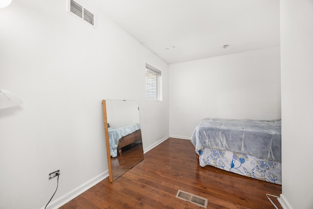 bedroom with visible vents, baseboards, and wood finished floors