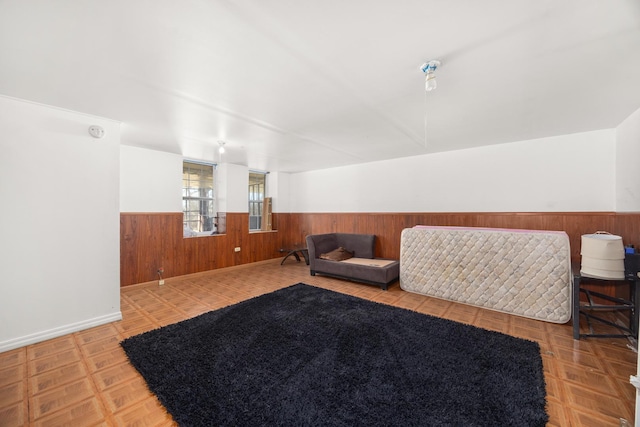 sitting room with baseboards, wood walls, and a wainscoted wall