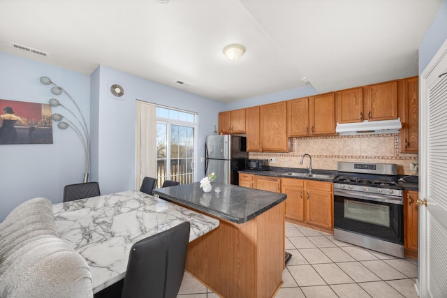 kitchen featuring backsplash, visible vents, a sink, under cabinet range hood, and stainless steel appliances