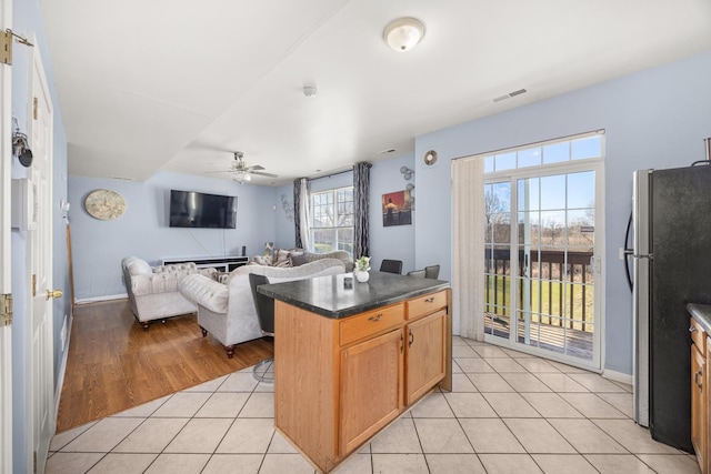 kitchen with visible vents, freestanding refrigerator, dark countertops, ceiling fan, and light tile patterned floors