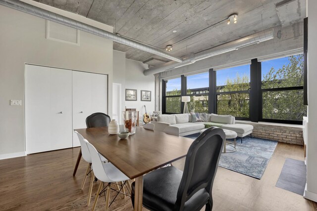 dining area with visible vents, a high ceiling, and wood finished floors