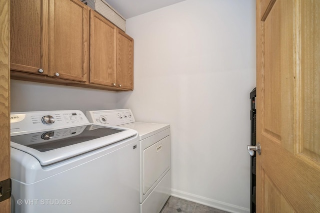 washroom featuring baseboards, cabinet space, and independent washer and dryer