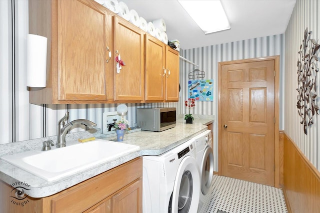 laundry area featuring cabinet space, independent washer and dryer, a sink, tile patterned floors, and wallpapered walls