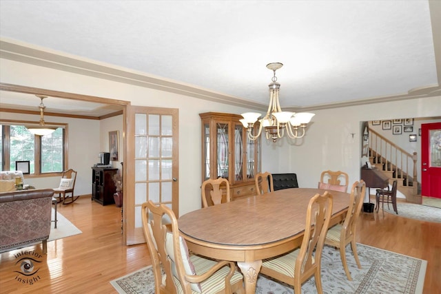 dining room with a chandelier, light wood-style flooring, baseboards, ornamental molding, and stairway