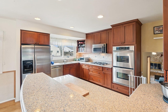 4569 Gettysburg Dr, Rolling Meadows, IL 60008 - kitchen featuring appliances with stainless steel finishes, light stone counters, a sink, brown cabinetry, and backsplash