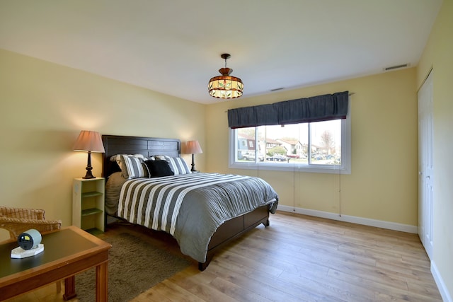 bedroom with baseboards, hardwood / wood-style flooring, and visible vents