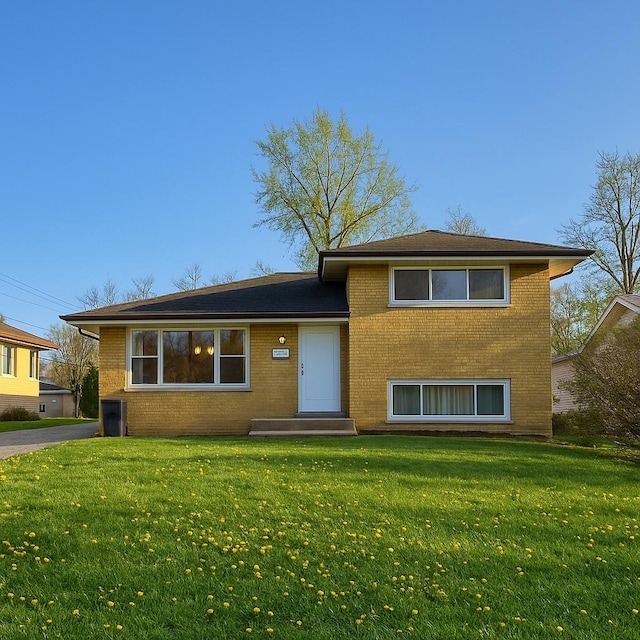 split level home featuring brick siding, a front yard, and entry steps