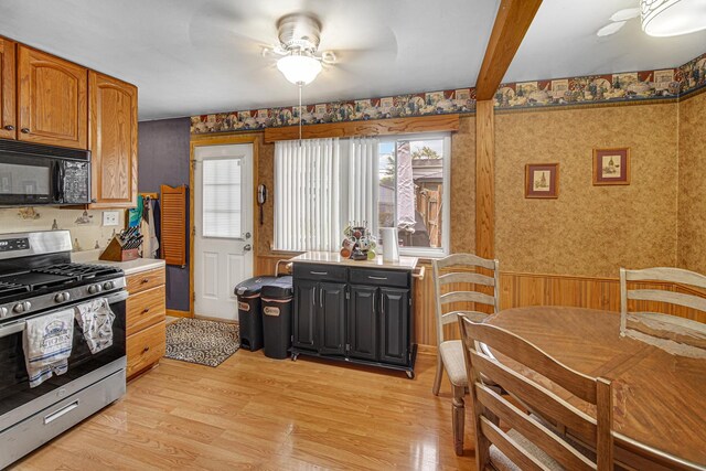 19605 Redwood Ln, Mokena, IL 60448 - kitchen featuring stainless steel range with gas cooktop, a wainscoted wall, a healthy amount of sunlight, black microwave, and a ceiling fan