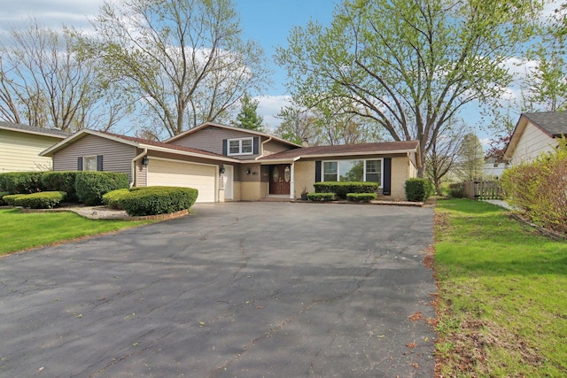 traditional-style home with a garage, a front lawn, aphalt driveway, and fence