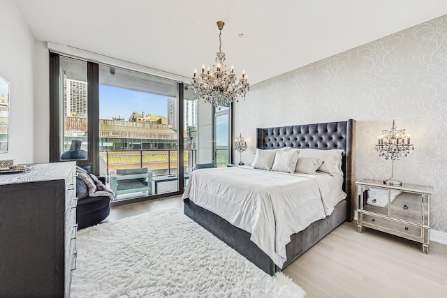 bedroom with access to outside, wallpapered walls, an inviting chandelier, and wood finished floors