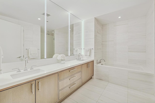 full bathroom featuring visible vents, a sink, double vanity, and a relaxing tiled tub