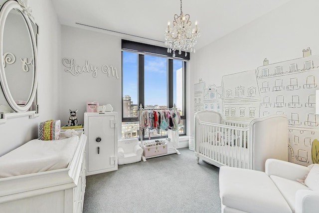 bedroom with an inviting chandelier, a crib, and carpet