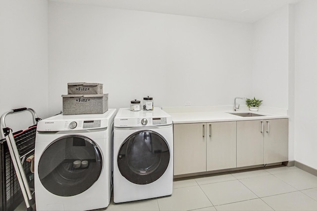 laundry area featuring cabinet space, independent washer and dryer, a sink, baseboards, and light tile patterned floors