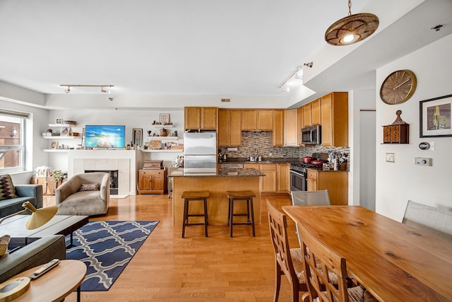 interior space with a tiled fireplace, light wood finished floors, and rail lighting