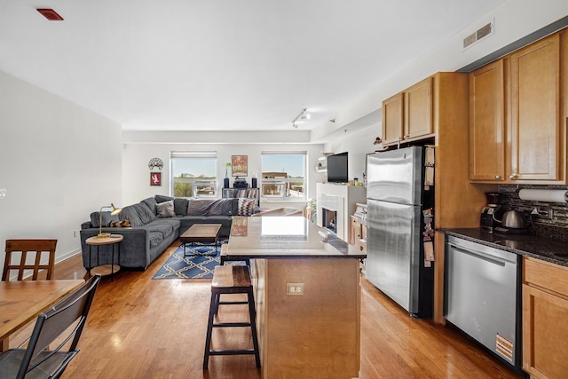 kitchen with a kitchen breakfast bar, visible vents, appliances with stainless steel finishes, light wood finished floors, and open floor plan