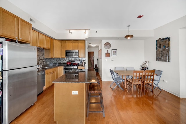 kitchen with visible vents, a kitchen bar, light wood-type flooring, a sink, and stainless steel appliances