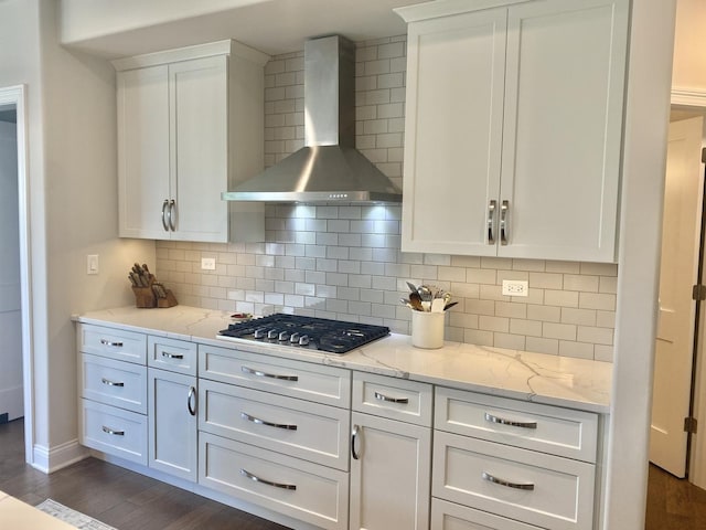 kitchen with wall chimney range hood, white cabinetry, stainless steel gas stovetop, and dark wood finished floors