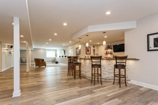 bar featuring wood finished floors, pendant lighting, indoor bar, baseboards, and recessed lighting
