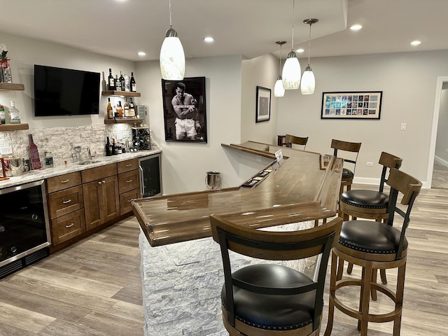 bar featuring wine cooler, wet bar, light wood-type flooring, recessed lighting, and backsplash