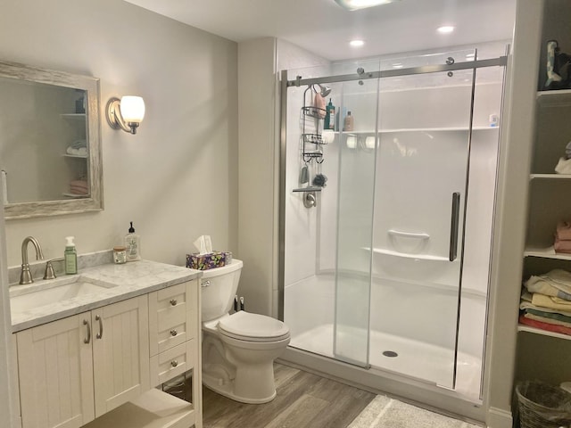 full bath with vanity, toilet, wood finished floors, and a stall shower