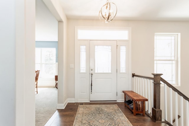 foyer with dark wood-style flooring, baseboards, and a notable chandelier