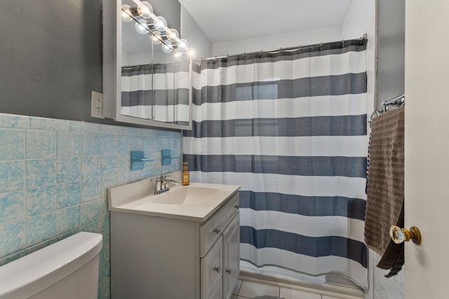 bathroom featuring toilet, vanity, tile walls, a shower with curtain, and a wainscoted wall