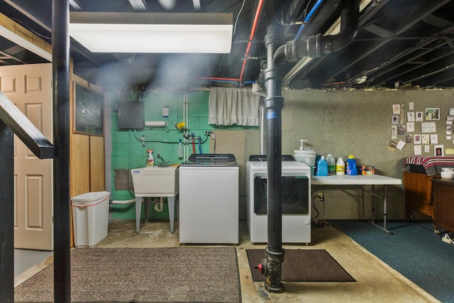 unfinished below grade area featuring washing machine and clothes dryer, electric panel, and a sink