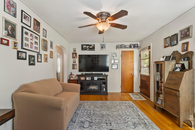 living room featuring ceiling fan, arched walkways, and wood finished floors